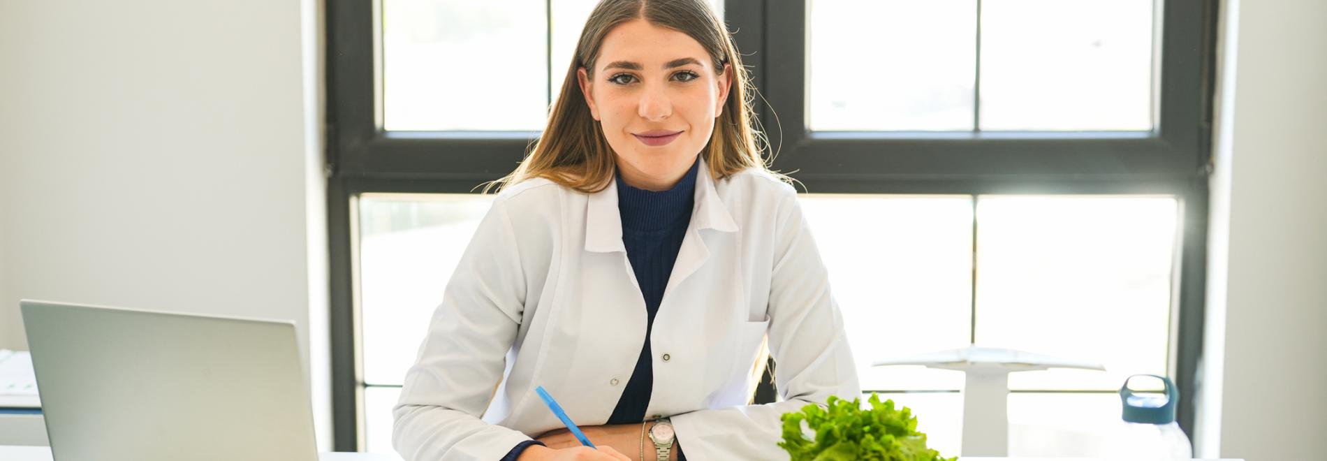 Woman in a labcoat taking notes on a clipboard