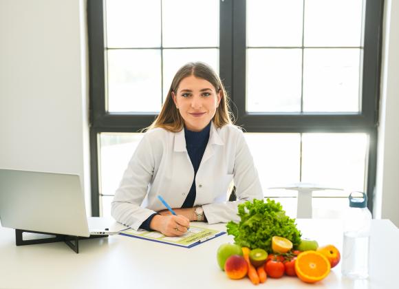 Woman in a labcoat taking notes on a clipboard