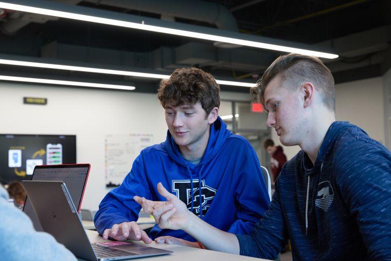 two students working together in front of a laptop