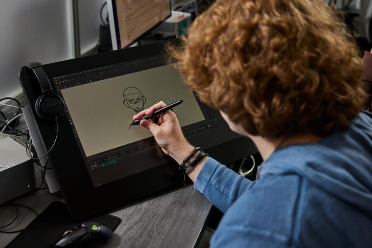 Student drawing a character on a digital art tablet