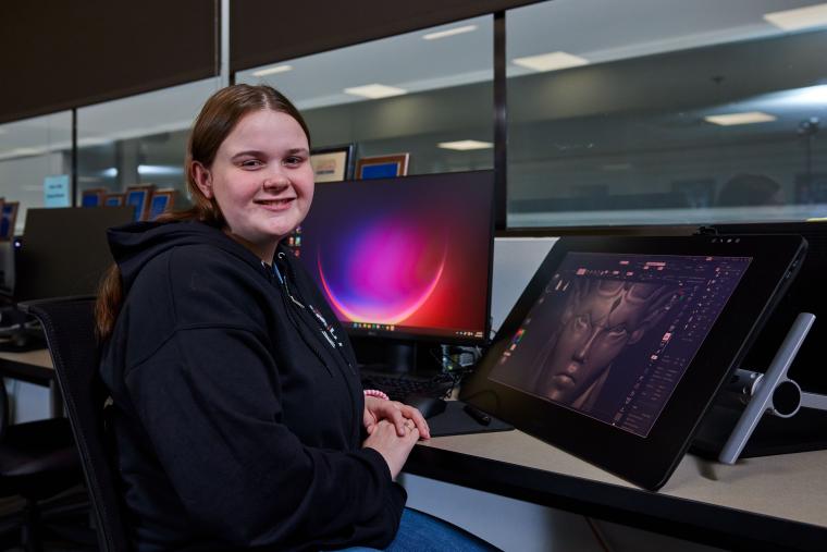 Student sitting next to digital art workstation