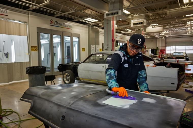 Student refinishing car trunk cover