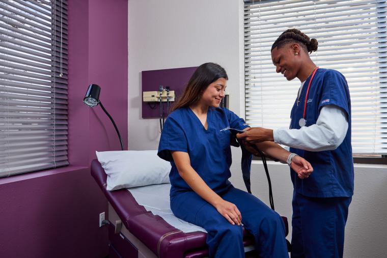 Student practicing checking blood pressure on another student