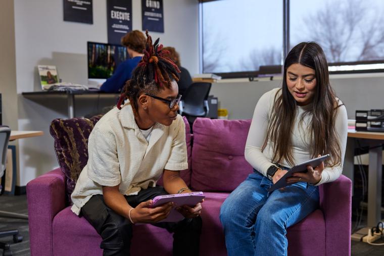 Two students exchanging ideas using tablets