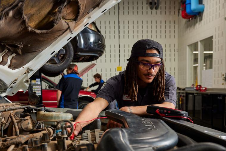 Student troubleshooting car with multimeter