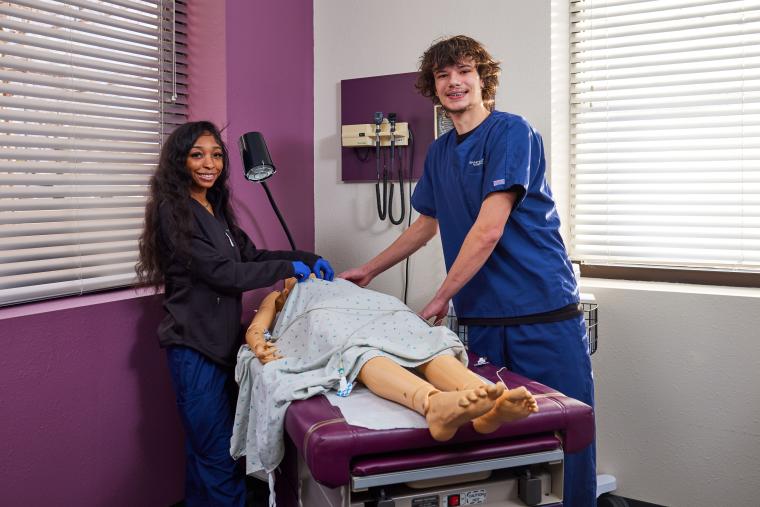 Two students installing sensor probes on a medical dummy