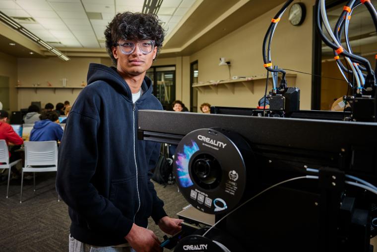 Student standing in front of a 3D printer