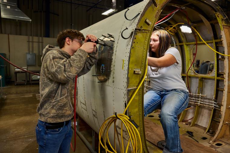 Two students installing window onto plane