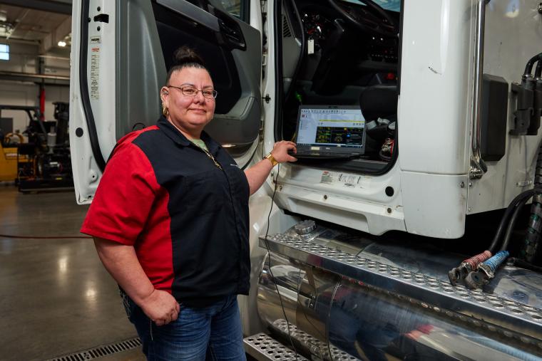 Student using a laptop to read diagnostic information from a semi truck