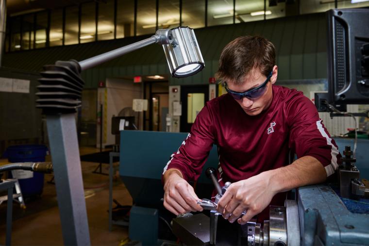 Student measuring a part with calipers