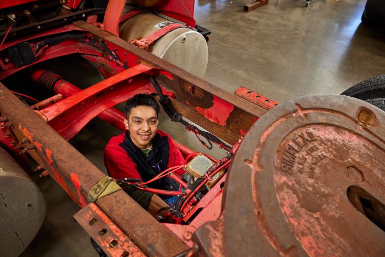 Student inspecting wires near the trailer hitch on a semi truck