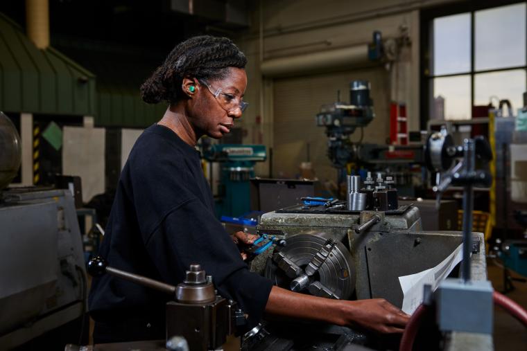 Student reading a document attached to the top of a lathe