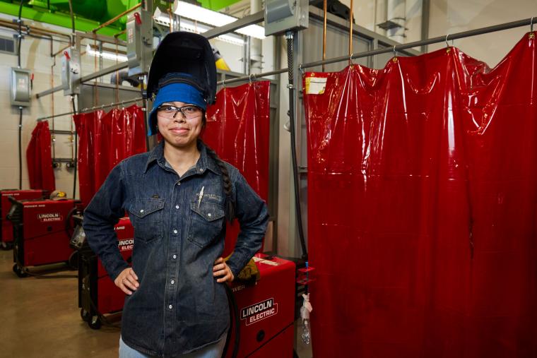 Student standing in front of several welding stations