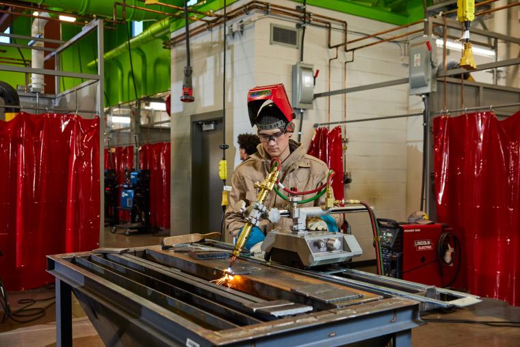 Student using a table welder to cut a steel sheet
