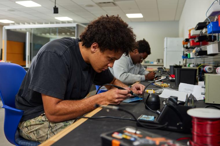 Student soldering pins on circuit board