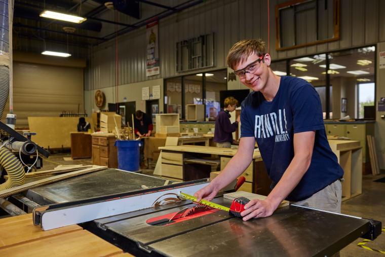Student setting table saw for cutting wood board