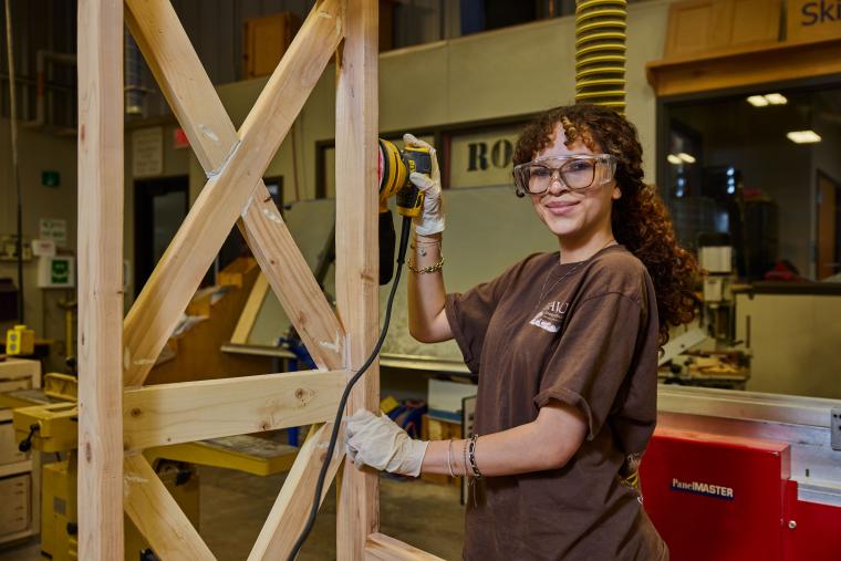 Student sanding wooden post