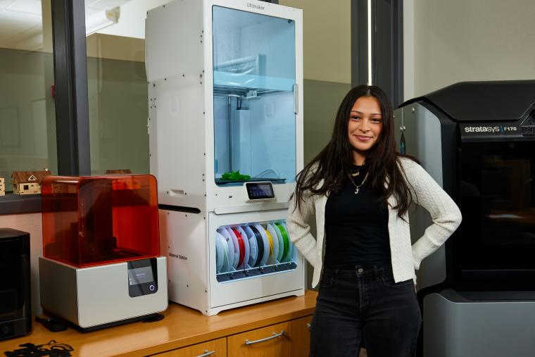 Student standing in front of several 3D printers