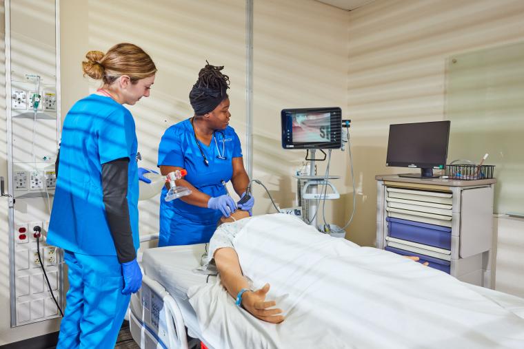 Two students practicing using an endoscopic camera on a training mannequin