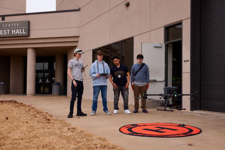 Four students practicing flying a drone