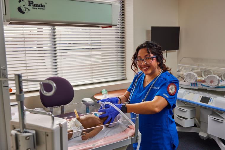 Student praciticing applying a breathing mask to a model infant