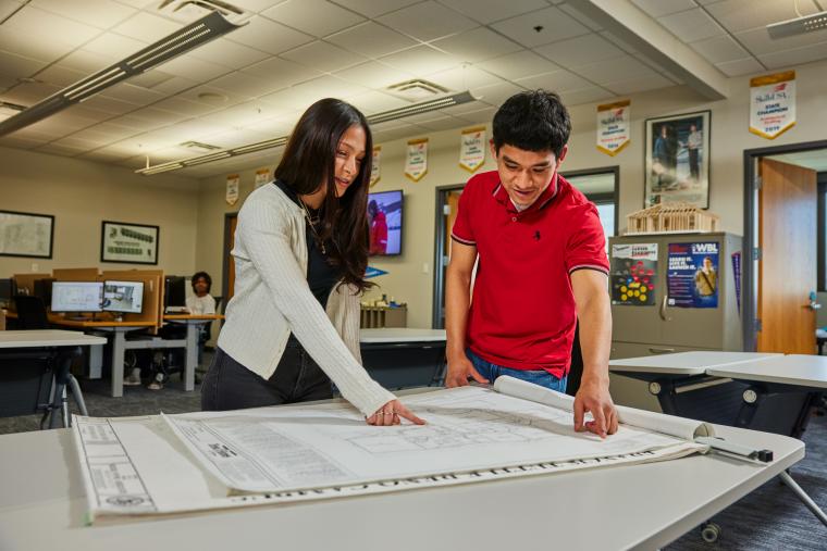 Two students reviewing building blueprints