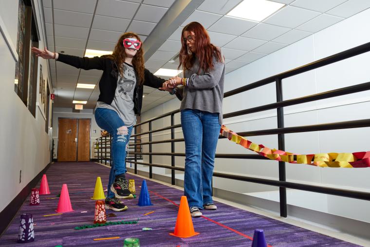 One student guiding another blindfolded student through an obstacle course