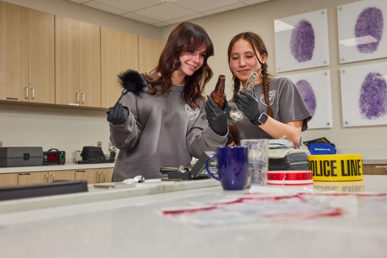 Students dusting for fingerprint samples off of glass bottles