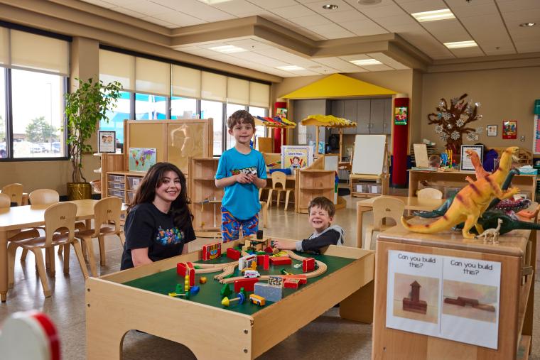 Student and two kids playing with a toy train set