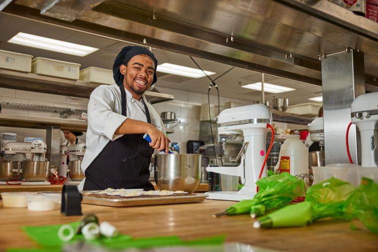Student scooping dough from mixing bowl