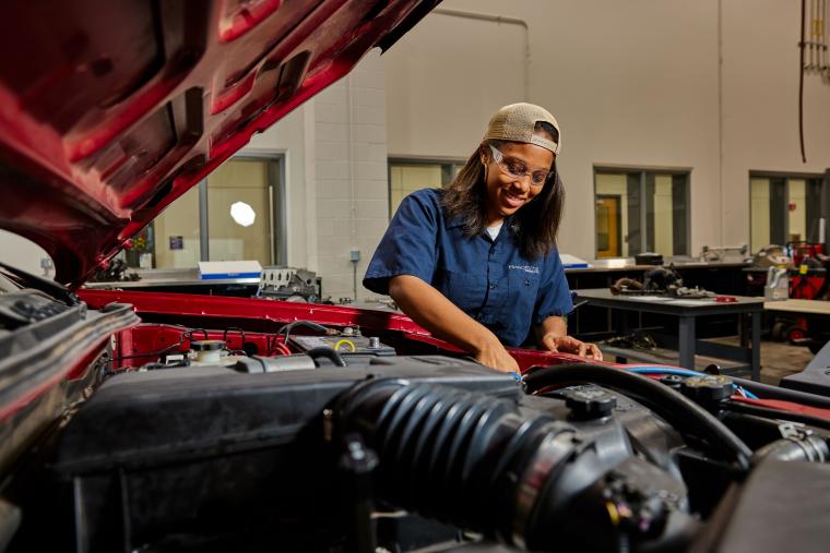 Student working on car from under the hood