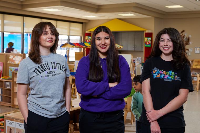 Three students standing together in the early childhood development classroom