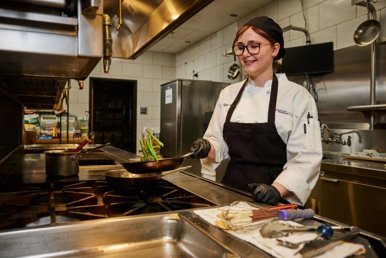Student cooking asparagus over a stove