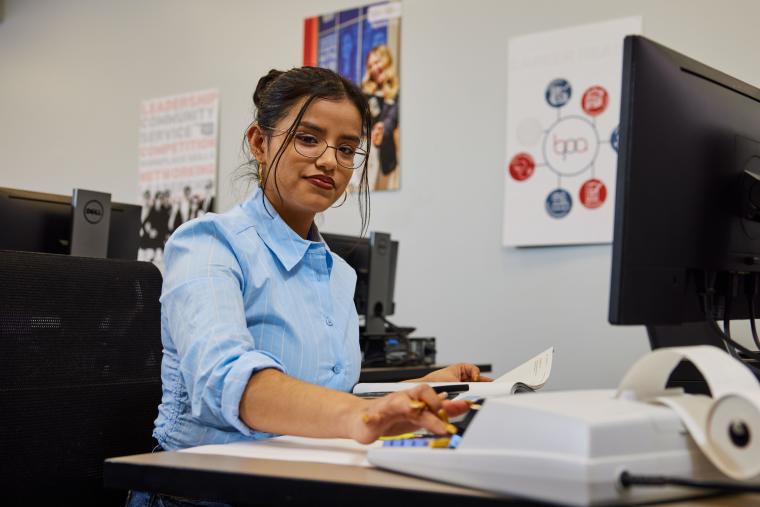 Student keying numbers into a desktop calculator