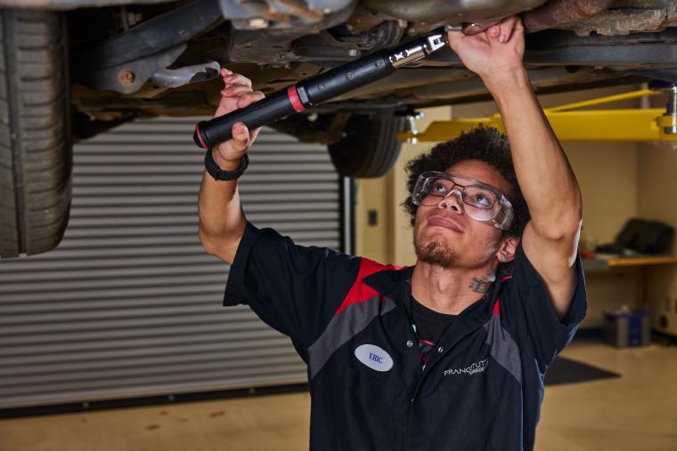Student working on the underside of a car