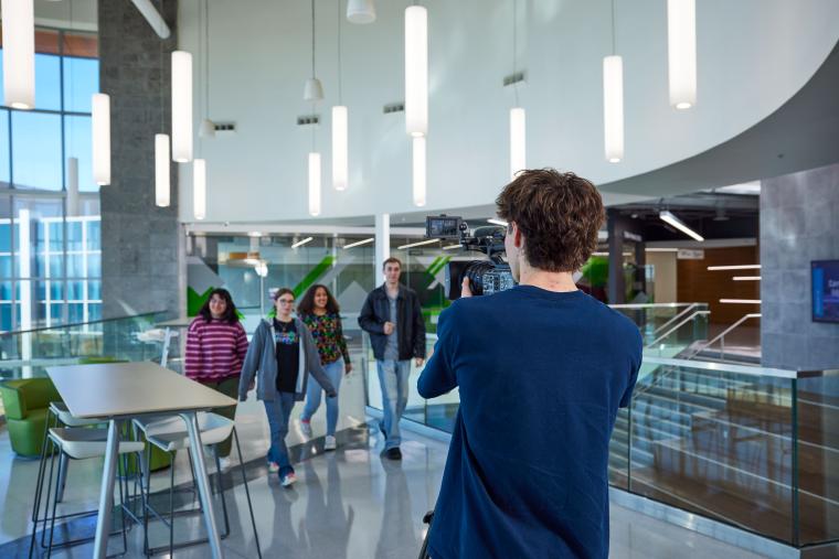 Student recording a group of students using a large video camera