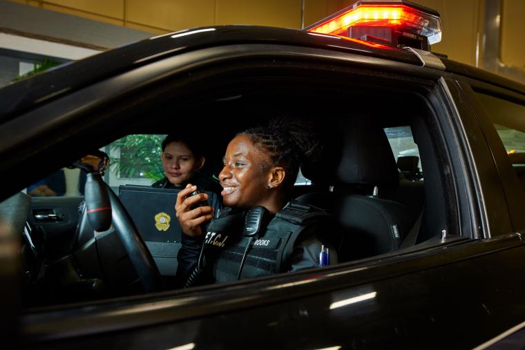 Two students practicing radio operation in a police car