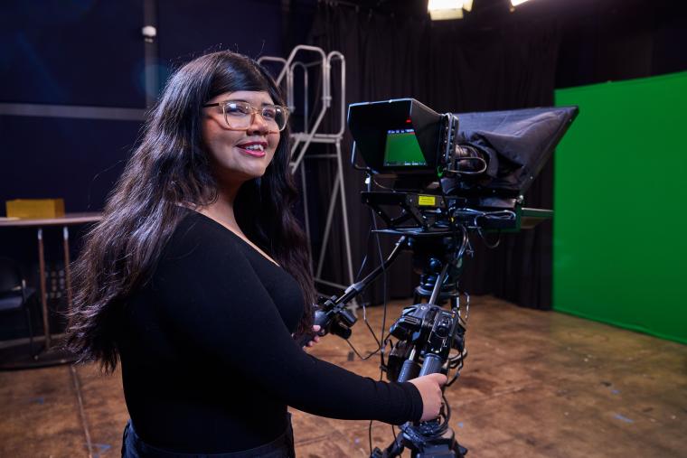 Student operating a cinematic camera on a tripod