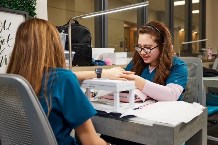 Student inspecting another student's nail clip ons