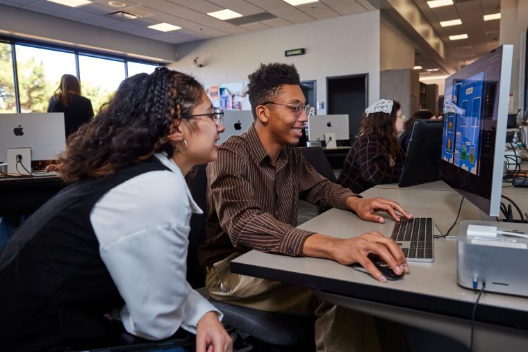 Two students working on a digital flyer