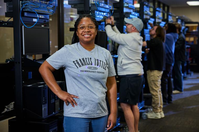 Student standing in front of several server racks