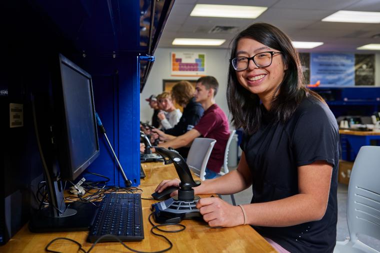 Student operating a computer with a flight joystick