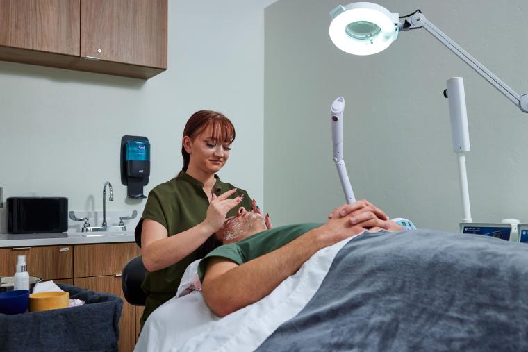 Student applying skincare products to customer's face