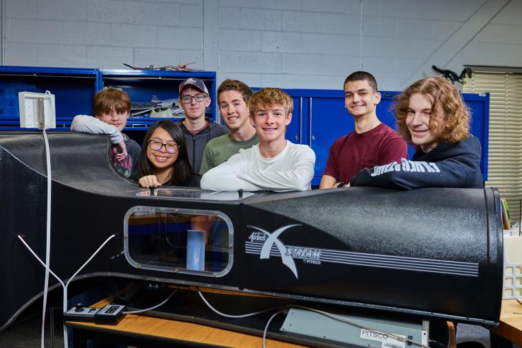 Several students standing behind a wind tunnel