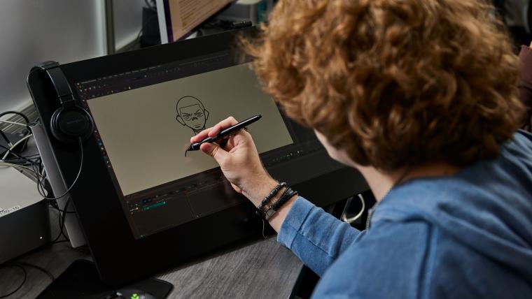 Student drawing a character on a digital art tablet
