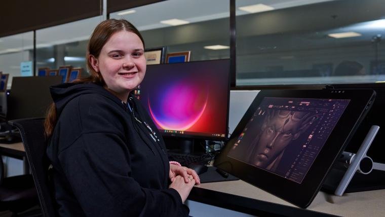 Student sitting next to digital art workstation