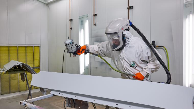 Student in protective gear painting car parts