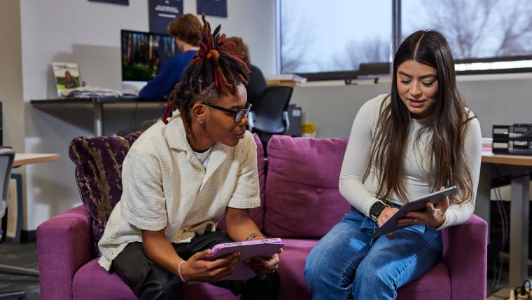 Two students exchanging ideas using tablets