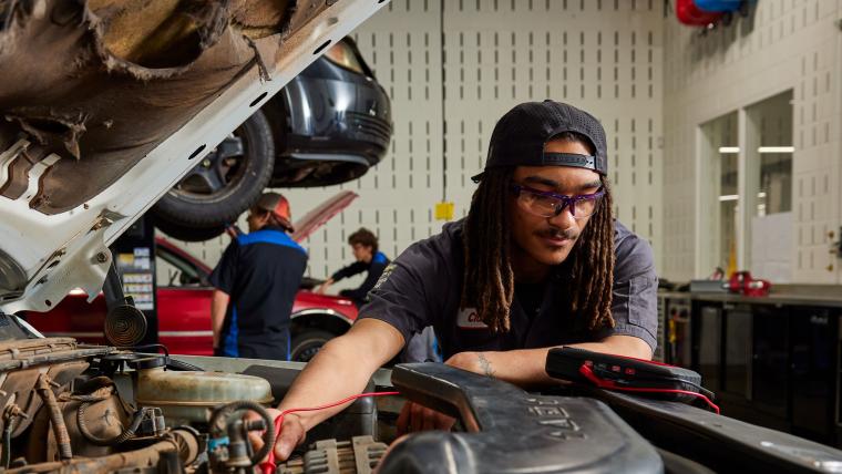 Student troubleshooting car with multimeter