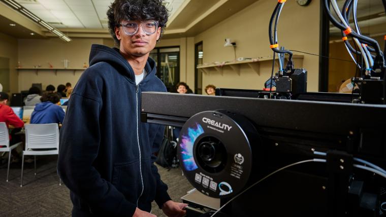 Student standing in front of a 3D printer